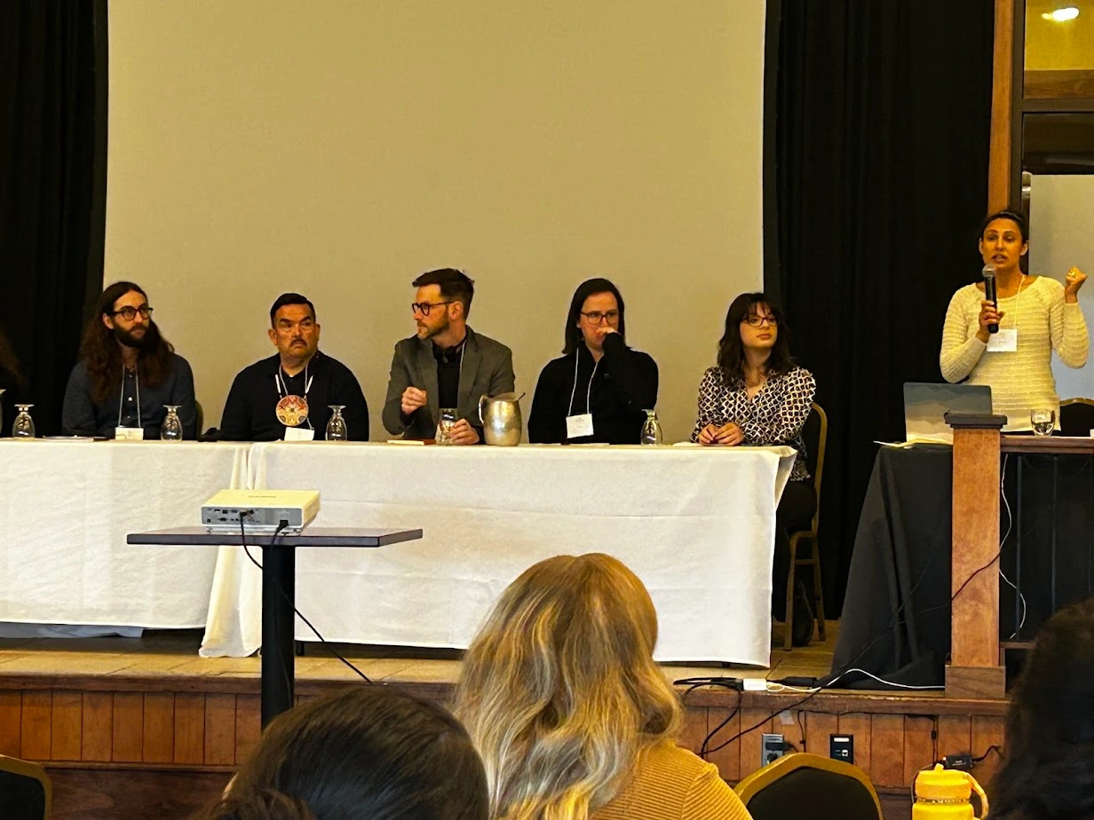 Close view of panelists seated at a table on stage during an environmental education discussion at the NBEN Symbiosis conference.